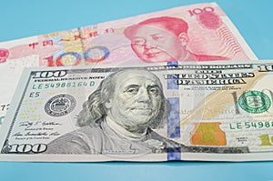 100 dollar bill and 100 yuan on a blue background.