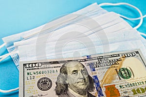 100 dollars banknote lie on medical masks on blue background. Concept of deficit, speculation and sold out of face masks