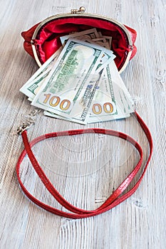 100 dollars banknotes fall out from red handbag