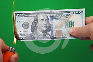 100 dollars burning on a green background. Concept of downturn in economy and loss