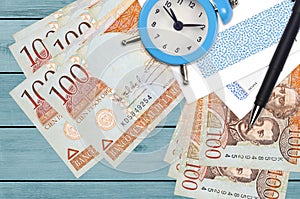 100 Dominican peso bills and alarm clock with pen and envelopes. Tax season concept, payment deadline for credit or loan.