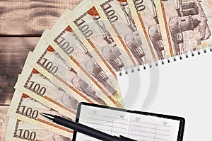 100 Dominican peso bills fan and notepad with contact book and black pen. Concept of financial planning and business strategy