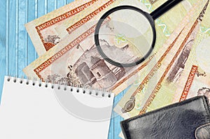 100 Dominican peso bills and magnifying glass with black purse and notepad. Concept of counterfeit money. Search for differences