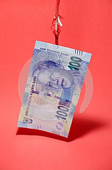 100 Rand note hanging by a thread