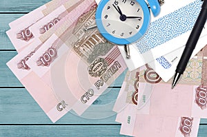 100 russian rubles bills and alarm clock with pen and envelopes. Tax season concept, payment deadline for credit or loan.