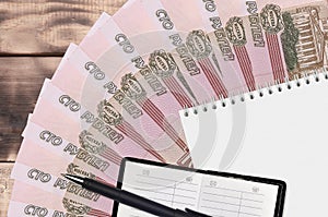 100 russian rubles bills fan and notepad with contact book and black pen. Concept of financial planning and business strategy