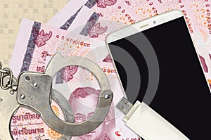 100 Thai Baht bills and smartphone with police handcuffs. Concept of hackers phishing attacks, illegal scam or malware soft