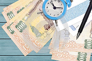 100 Ukrainian hryvnias bills and alarm clock with pen and envelopes. Tax season concept, payment deadline for credit or loan.