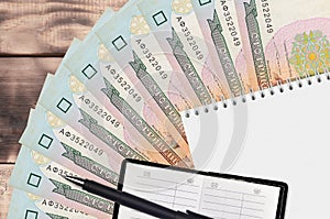 100 Ukrainian hryvnias bills fan and notepad with contact book and black pen. Concept of financial planning and business strategy