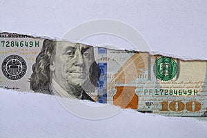100 US dollar banknote in torn paper hole