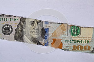 100 US dollar banknote in torn paper hole