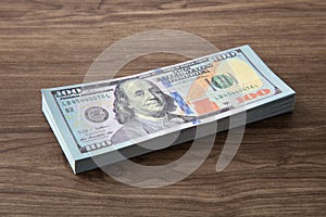 100 US Dollar bills stack on wooden table