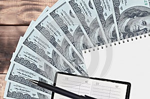 100 US dollars bills fan and notepad with contact book and black pen. Concept of financial planning and business strategy