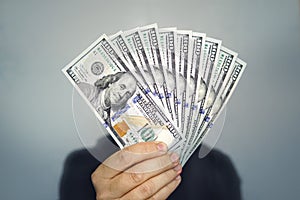 1000 dollars in 100 bills in a man`s hand close-up on a dark background. Hands holding dollar cash