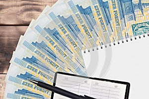 1000 Hungarian forint bills fan and notepad with contact book and black pen. Concept of financial planning and business strategy