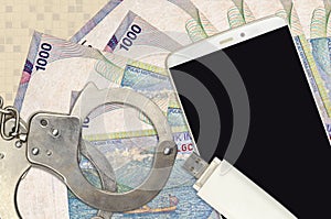 1000 Indonesian rupiah bills and smartphone with police handcuffs. Concept of hackers phishing attacks, illegal scam or malware