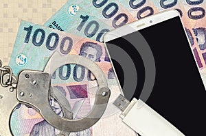 1000 Indonesian rupiah bills and smartphone with police handcuffs. Concept of hackers phishing attacks, illegal scam or malware