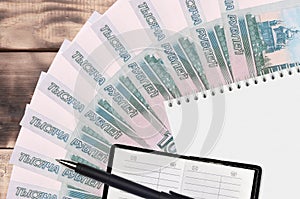 1000 russian rubles bills fan and notepad with contact book and black pen. Concept of financial planning and business strategy