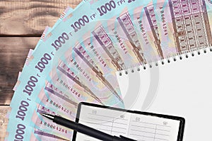 1000 Ukrainian hryvnias bills fan and notepad with contact book and black pen. Concept of financial planning and business strategy