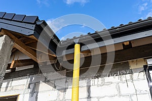 100mm diameter yellow PVC pipe connected to the end of the gutter on the roof, protected against water.