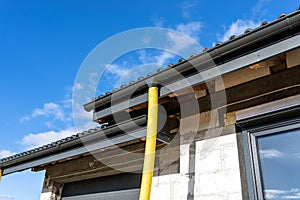 100mm diameter yellow PVC pipe connected to the end of the gutter on the roof, protected against water.