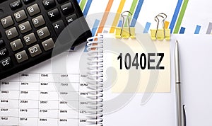 1040 EZ text, written on a sticker with calculator,pen on chart background