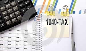 1040 TAX text, written on a sticker with calculator,pen on chart background