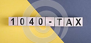 1040 tax Word Written on Wooden Cubes on yellow and gray background