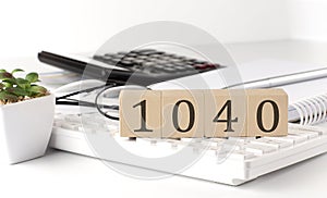 1040 written on a wooden cube on keyboard with office tools