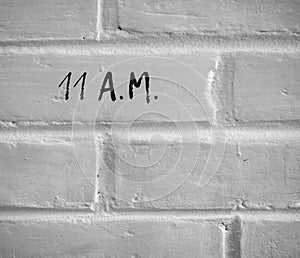 11 A.M. WRITTEN ON WHITE PLAIN BRICK WALL