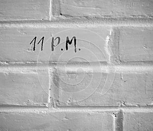 11 P.M. WRITTEN ON WHITE PLAIN BRICK WALL