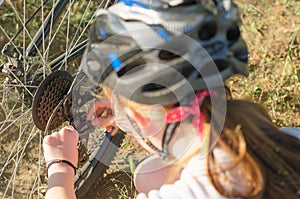 11-year-old girl repairs a bicycle in the countryside. Teenage girl repairing a bike while traveling