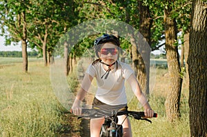 An 11-year-old girl rides a bicycle in the forest. A girl rides a bicycle along a forest path
