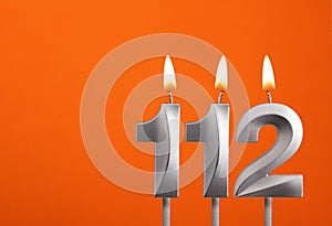 112 candle - Birthday celebration on orange background
