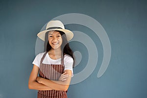 11s smiling young pretty girl portrait in summer hat and striped brown overall with blue cement wall