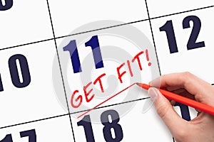 11th day of the month. Hand writing text GET FIT and drawing a line on calendar date. Save the date.