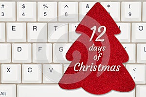 12 days of Christmas message on a red Christmas tree gift tag on a keyboard