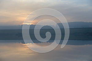 12 people walk along a dam wall in front of a hazy sunset at dusk