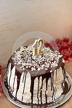 12 years birthday buffet. White cake with chocolate streaks and candles stay on table. Bat Mitzvah party. Vertical photo,