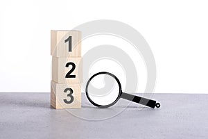 123 - numbers 1, 2, 3 on wooden cube blocks and magnifying glass on grey table