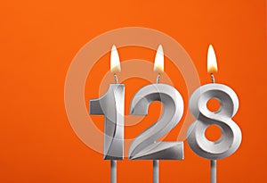 128 candle - Birthday celebration on orange background