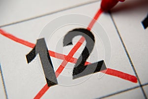 The 12st number in the calendar is crossed out with a red cross in a macro on a white sheet. Calendar for plans, notes