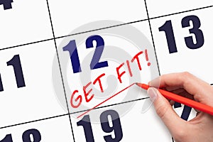 12th day of the month. Hand writing text GET FIT and drawing a line on calendar date. Save the date.
