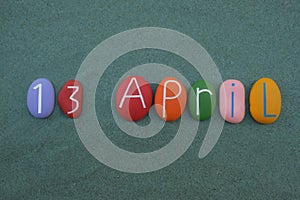 13 April, calendar date composed with colored and carved stones over green sand
