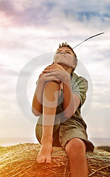 13 years old boy on a Bale of Hay in Field