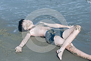 13 years old boy relaxation on the sand on the beach in the sea waves. Concept of family summer vacation