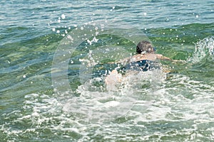 13 years old boy swimming and relaxation in the sea waves. Concept of family summer vacation.