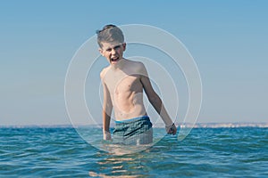 13 years old boy throws up his hands and screaming in the sea waves. Concept