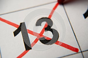 The 13st number in the calendar is crossed out with a red cross in a macro on a white sheet. Calendar for plans, notes