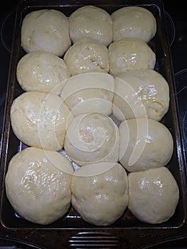 15 round raw egg dough balls on a pan proofing